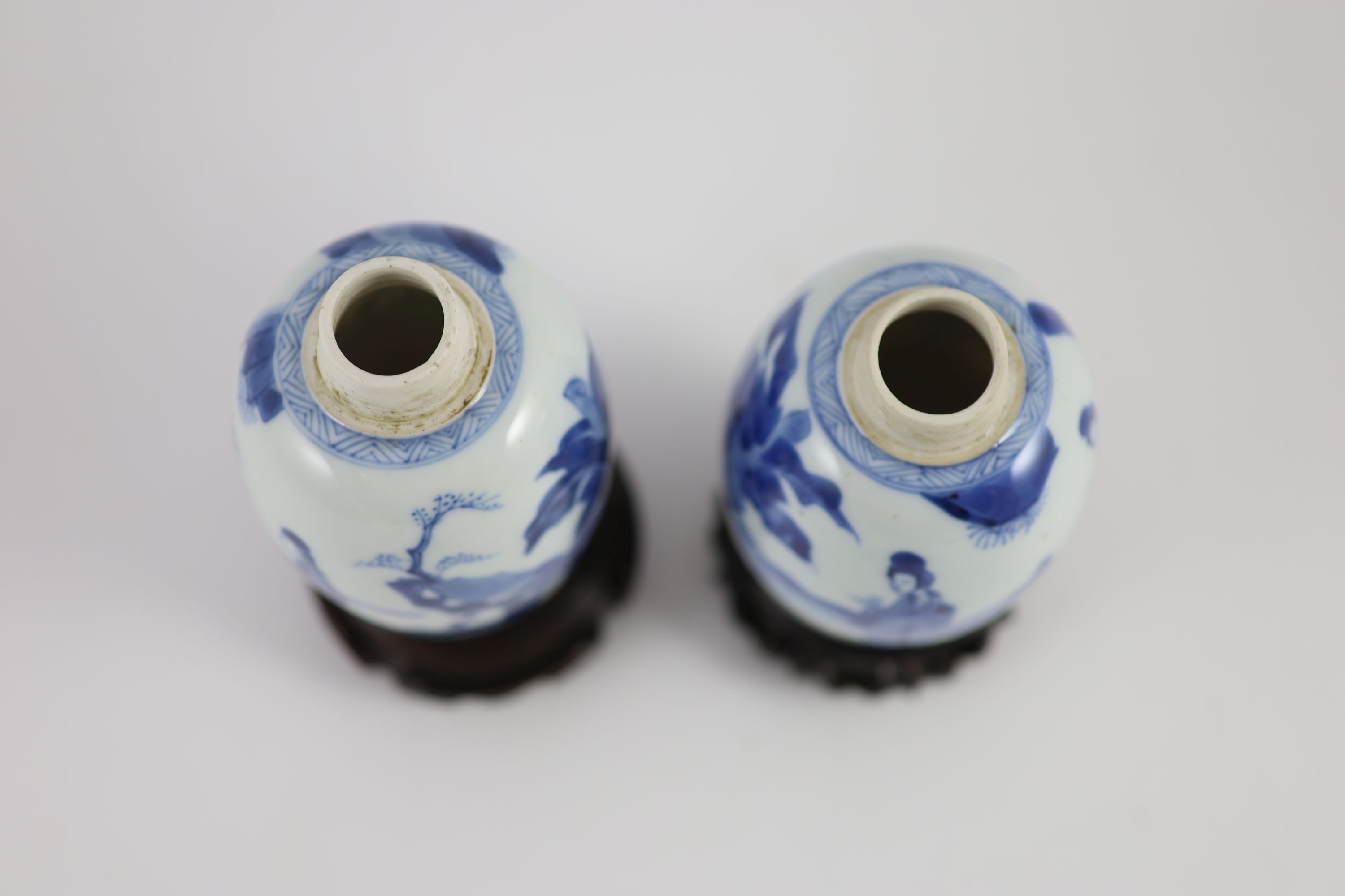 A pair of Chinese blue and white ovoid jars and covers, Kangxi period, 13.2 and 13.5 cm high, wood stands